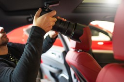 Professional photographer with a camera taking pictures of a car's interior.